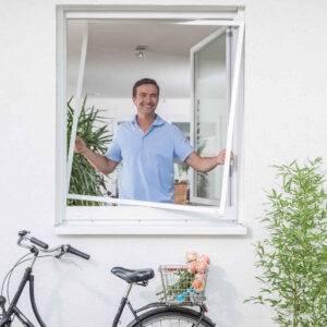 Ein Mann setzt ein Fliegengitter in ein Fenster ein